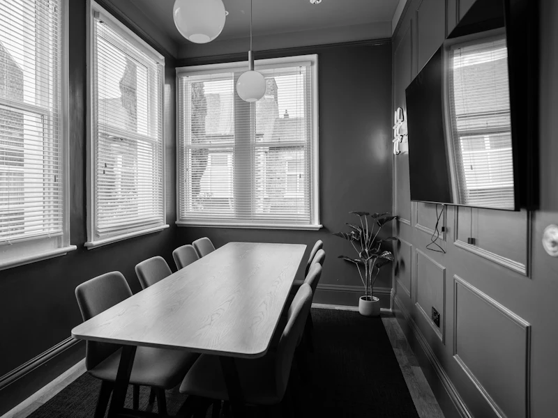 An empty meeting room with a long wooden table and green walls